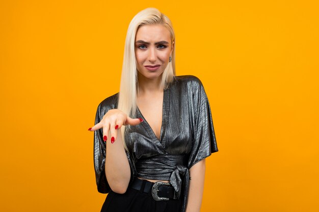 Portrait of a blond lady showing her displeasure and disagreement on a yellow background