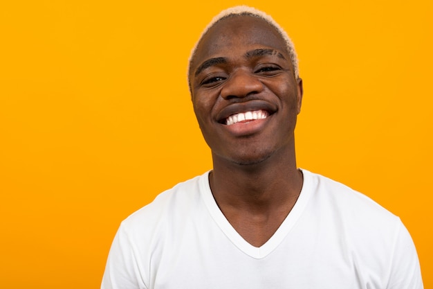 Foto ritratto di un uomo di colore africano carismatico sorridente biondo in una maglietta bianca sull'arancia