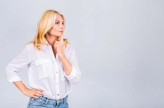 Portrait of blond stressed tired ill mature senior woman isolated on grey white color background.