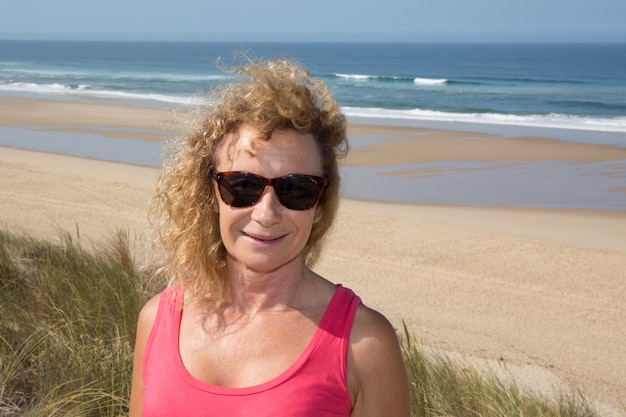 Portrait of a blond woman in sun glasses on the beach