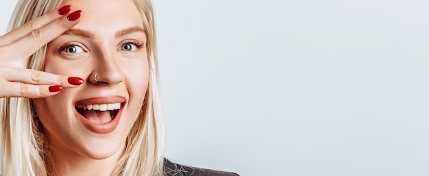 Portrait of blond woman winking happily showing peace victory gesture as fooling around, being optimistic