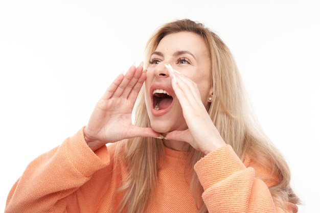 Portrait of blond young woman screaming into her palms on white studio background Important information news conceptxA