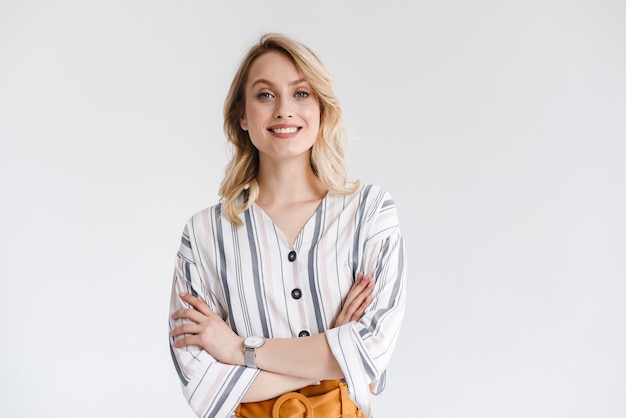 Photo portrait of blond young woman wearing casual clothes smiling with arms crossed isolated over white wall