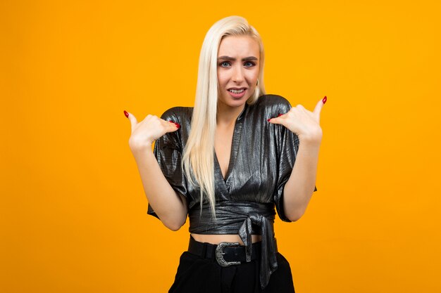 Portrait of blonde attractive mature young woman showing misunderstanding on orange studio space