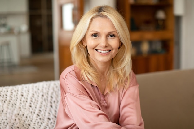 Portrait of blonde european mature woman posing smiling at home