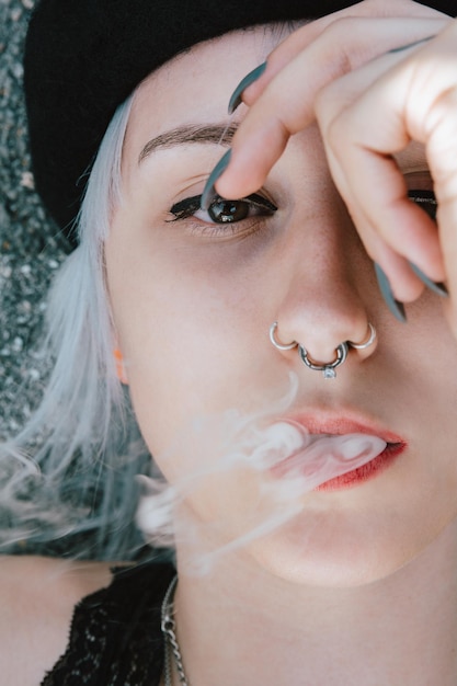 Portrait of a blonde female lying on the ground and smoking with her hand on her face