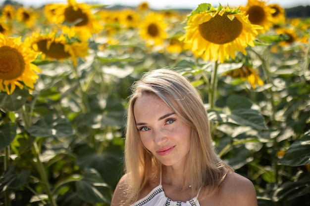 Portrait of a blonde girl closeup on a background of sunflowers