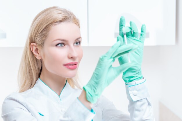 Portrait of a blonde girl in a medical gown with a syringe in her hands. Medical center advertisement. Mixed media