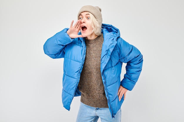 Portrait of blonde girl shouting loudly with hands news palms folded like megaphone isolated on white background