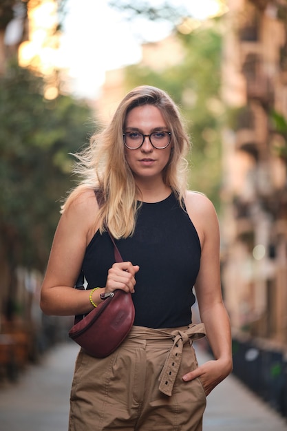 Ritratto di una ragazza bionda con gli occhiali in posa per un servizio fotografico in una strada della città di barcellona.