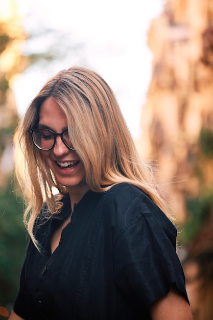 Portrait of a blonde girl with glasses posing for a photoshoot on a street in the city of Barcelona.