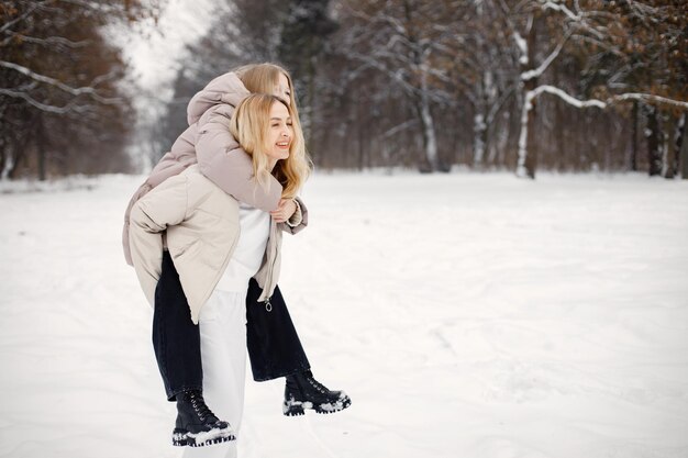 Portrait of blonde mother and teen daughter standing in winter forest