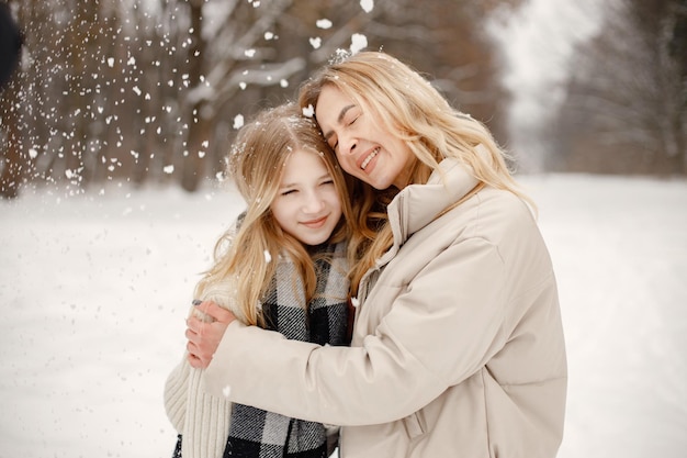 Portrait of blonde mother and teen daughter standing in winter forest