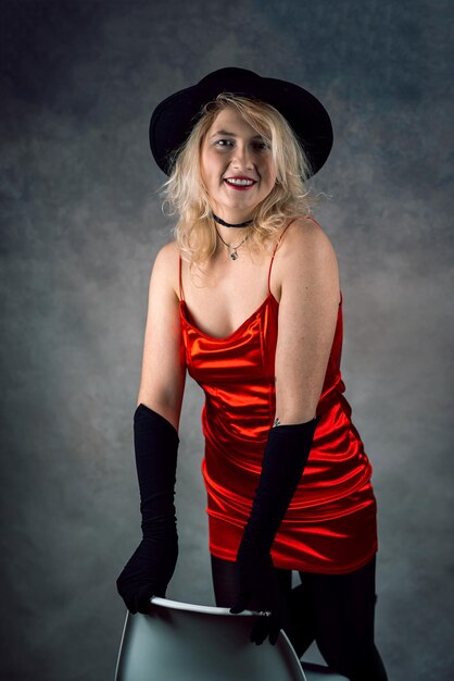 Portrait of blonde sexy lady in red dress and hat isolated grey background