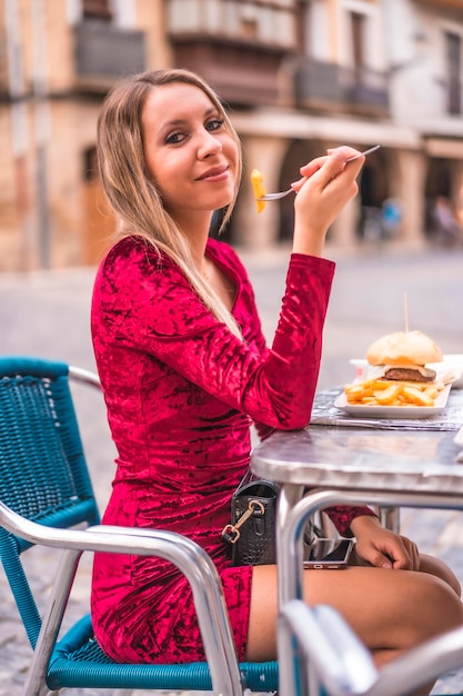 Portrait of a blonde woman eating lunch next to a medieval castle in summer