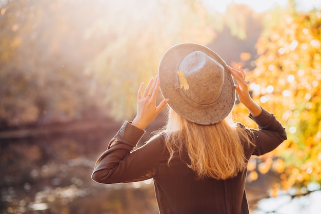 Portrait of a blonde woman in grey hat in autumn forest