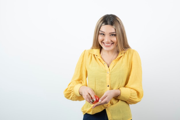 Portrait of blonde woman holding shiny red tomato