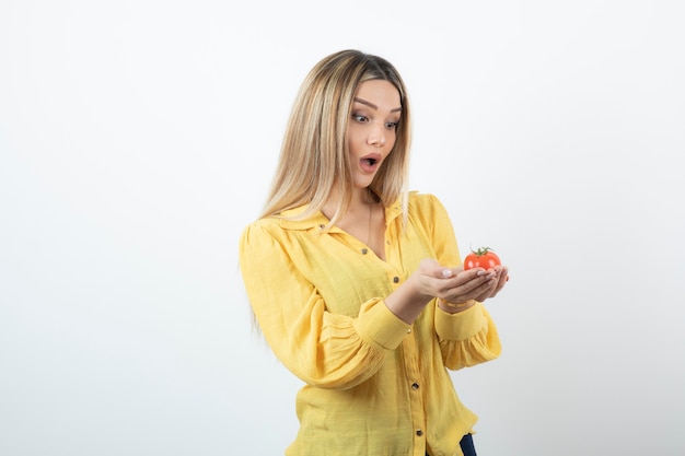 Portrait of blonde woman holding shiny red tomato