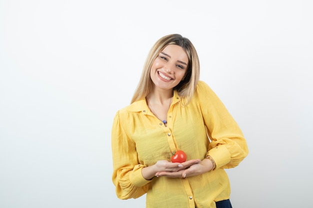 Portrait of blonde woman holding shiny red tomato