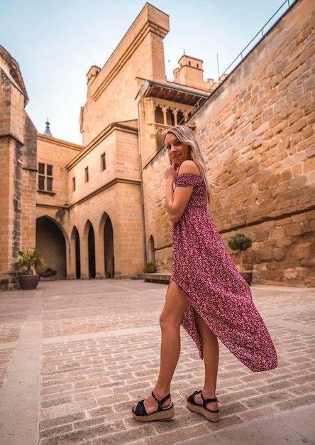 Portrait of a blonde woman in a medieval castle wearing a red dress enjoying