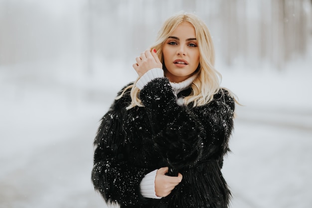 Portrait of blonde woman outside in snow winter coat