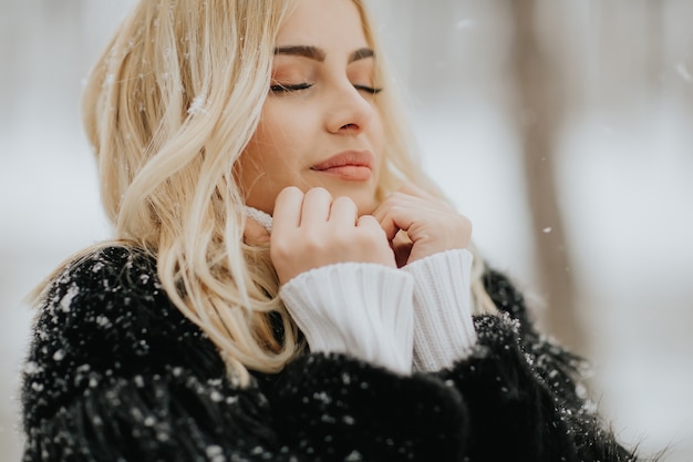 Portrait of blonde woman outside in snow winter coat