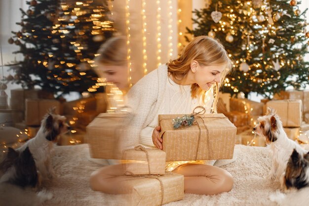 Portrait of a blonde woman sitting near Christmas tree with two yorkshire terriers