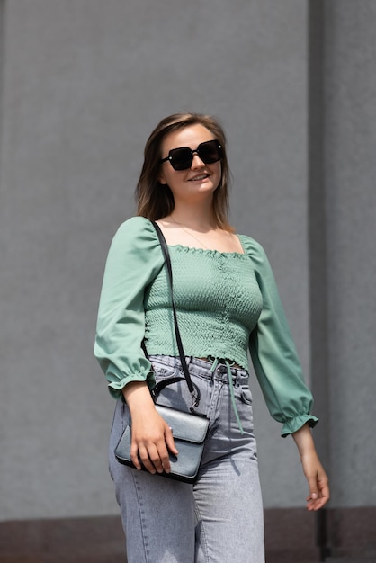 Portrait of a blonde woman in sunglasses on a background of a gray wall