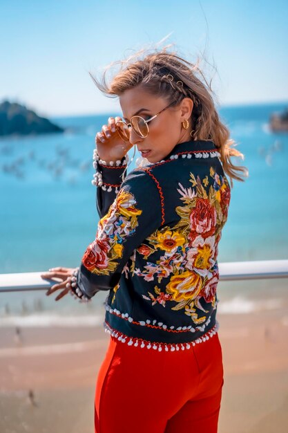 Portrait of a blonde woman on a terrace enjoying summer vacations with the sea in the background