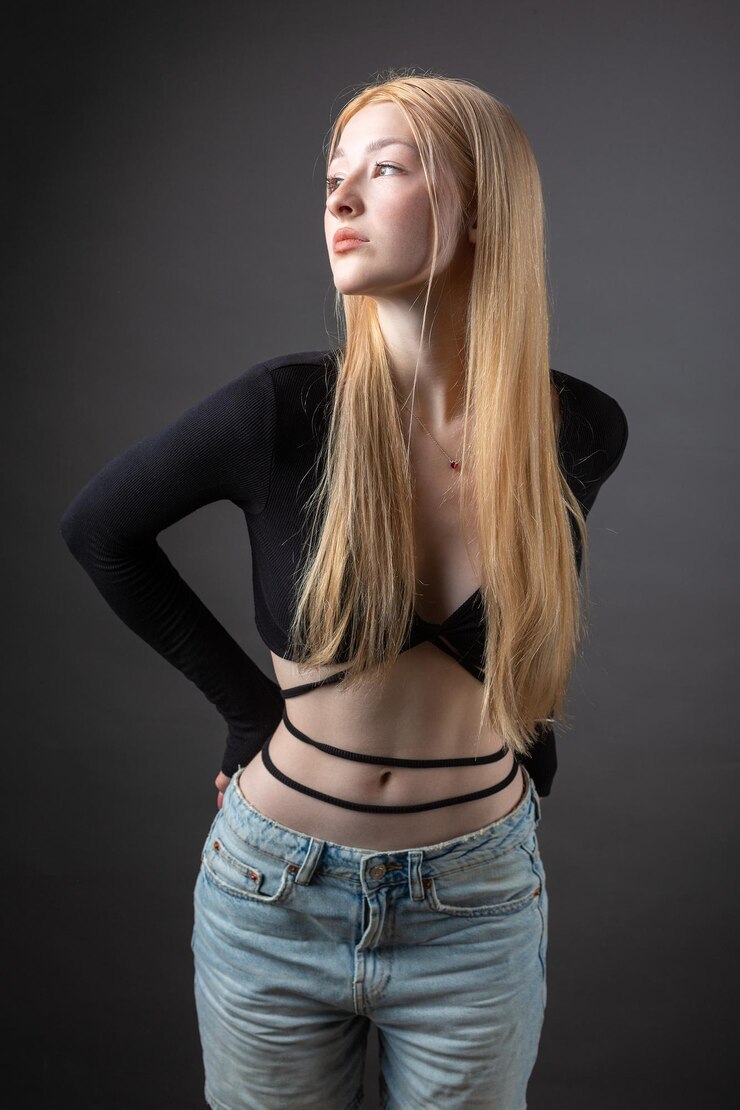 Portrait of a blonde woman with freckles in a sexy top and denim shorts in a studio