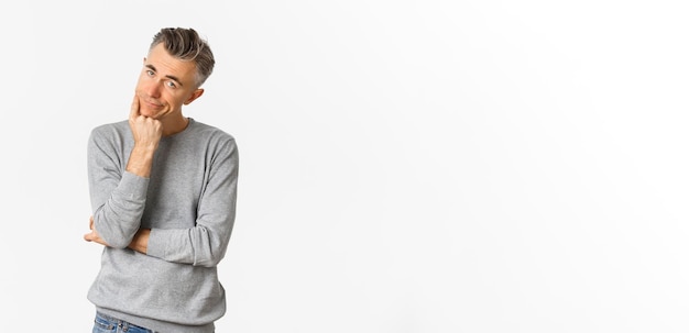 Portrait of bored and unamused middle-aged man in grey sweater leaning on hand and looking at            person