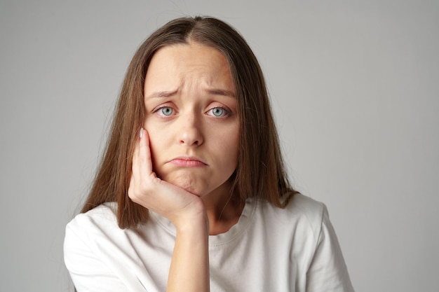 Portrait of a bored woman looking at camera on gray background