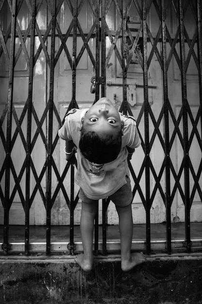portrait of boy bending against closed gate
