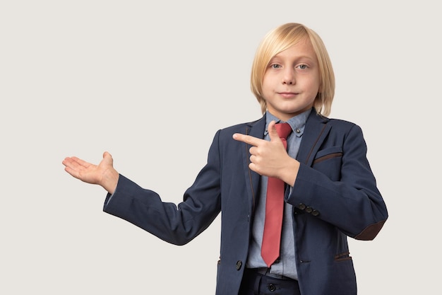 Portrait of a boy in a business suit pointing at something with his hand