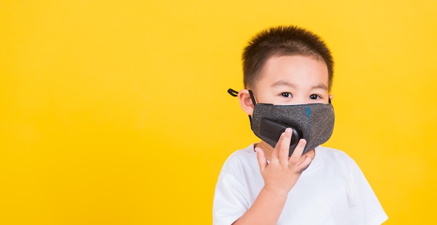 Portrait of boy covering face against yellow background