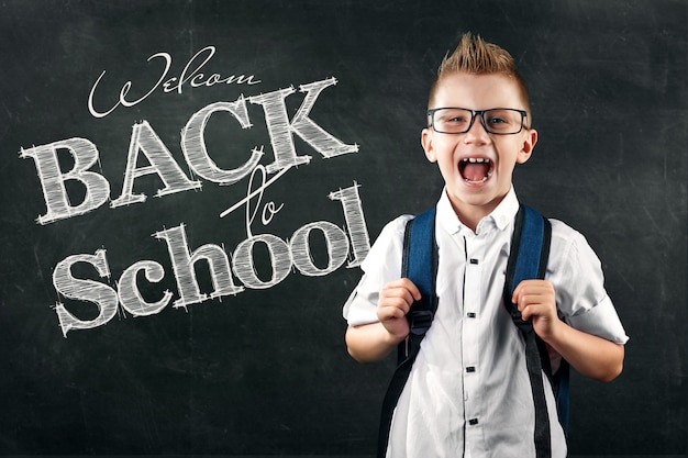 Портрет мальчика из начальной школы с надписью Back To School на школьной доске