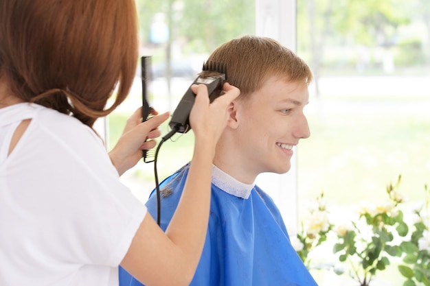 Portrait of boy getting haircut from female hairdresser at salon