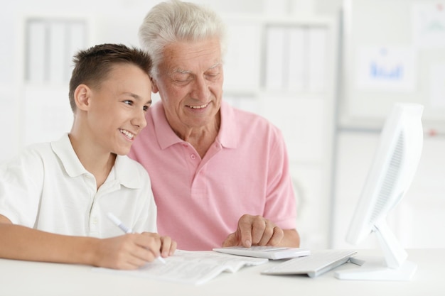 Photo portrait of a boy and grandfather with computer at home