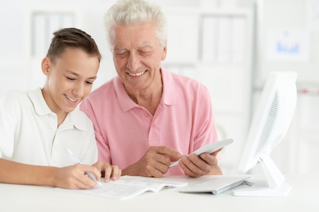 Photo portrait of boy and grandfather with computer