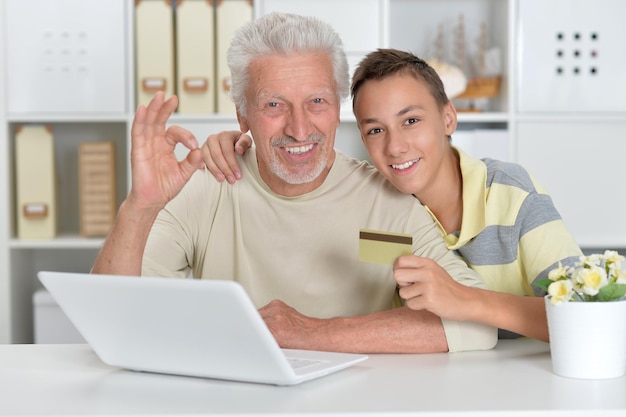 Portrait of  boy and  grandfather with a laptop and credit card at home