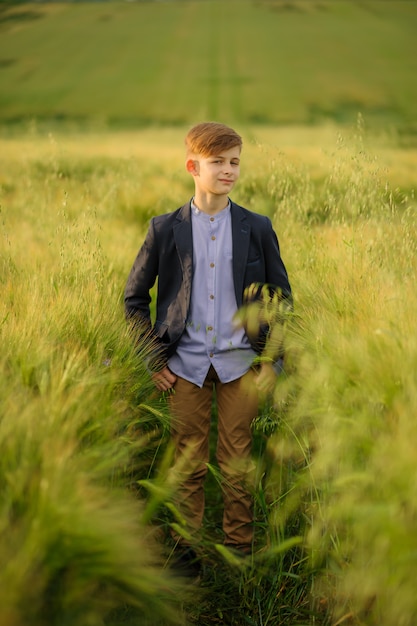 Ritratto di un ragazzo in un campo di grano verde.