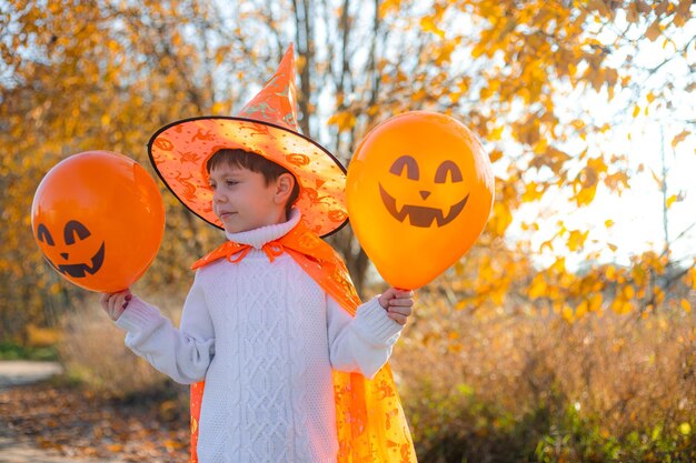 Portrait of a boy in Halloween clothes with pumpkin balloons on the street A traditional holiday October 31