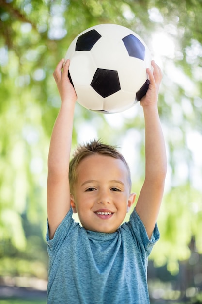 Ritratto del ragazzo che tiene un calcio in parco