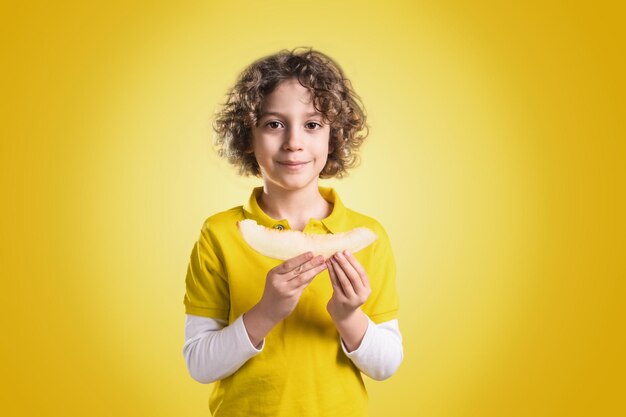 Portrait of boy holding fruit against yellow background