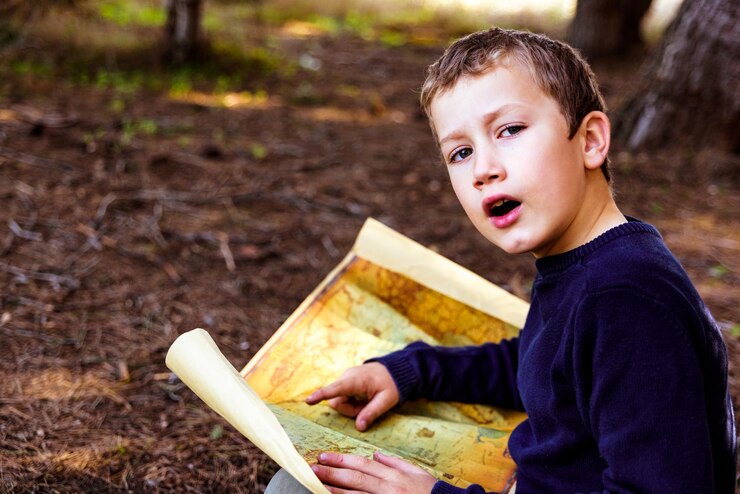 फोटो portrait of boy holding map on land
