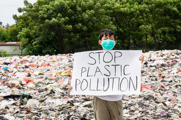 Foto ritratto di un ragazzo che tiene in mano un poster contro la spazzatura di plastica