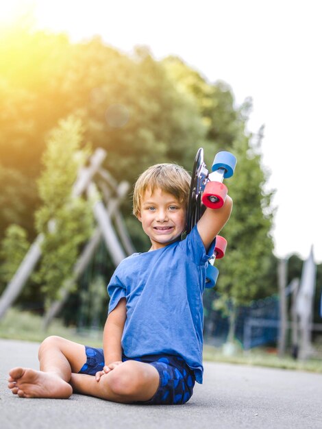 Photo portrait of boy holding skateboard on road