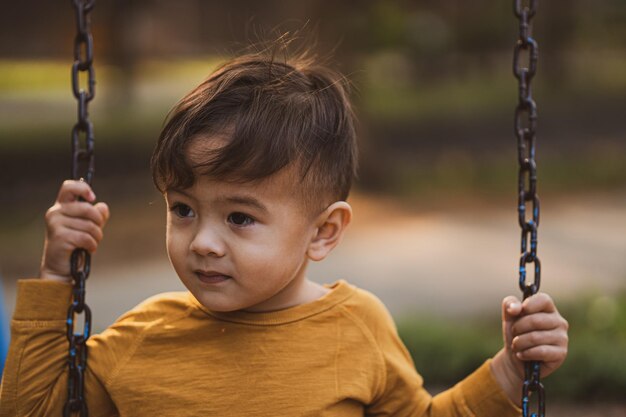 Portrait of boy holding swing at playground