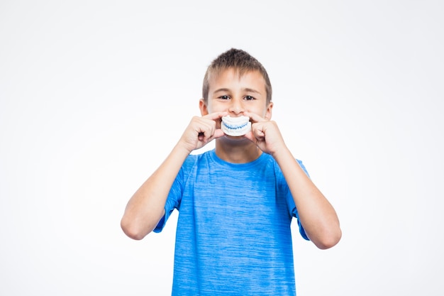 Photo portrait of a boy holding teeth plaster mold against white background