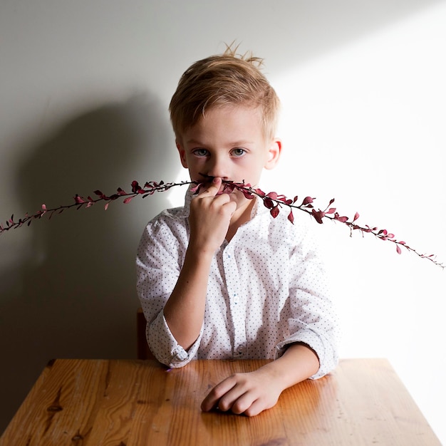 壁に鼻を張って枝を握っている男の子の肖像画